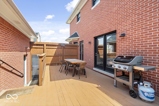 wooden terrace with grilling area, outdoor dining area, and fence