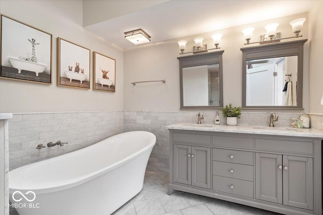 bathroom with double vanity, a wainscoted wall, a freestanding bath, and a sink