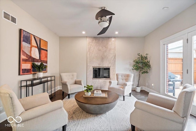 living room with wood finished floors, visible vents, a high end fireplace, and baseboards