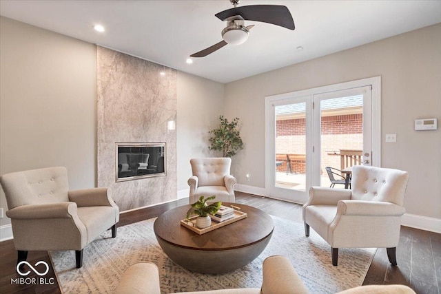 living area with wood finished floors, recessed lighting, a fireplace, baseboards, and ceiling fan