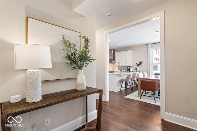 hallway featuring dark wood-type flooring and baseboards