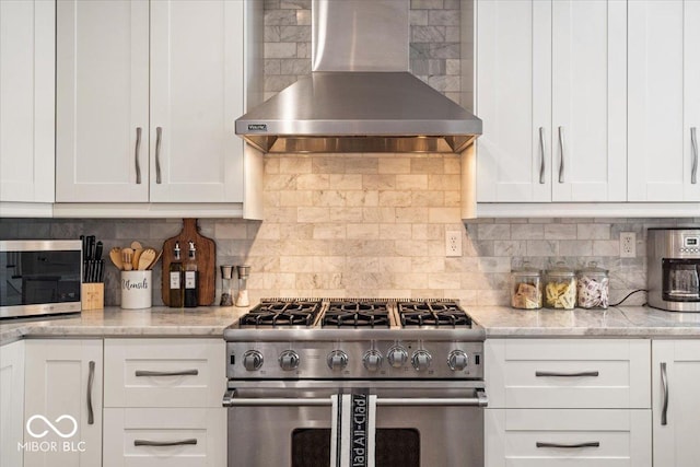 kitchen featuring stainless steel appliances, backsplash, white cabinets, and wall chimney range hood