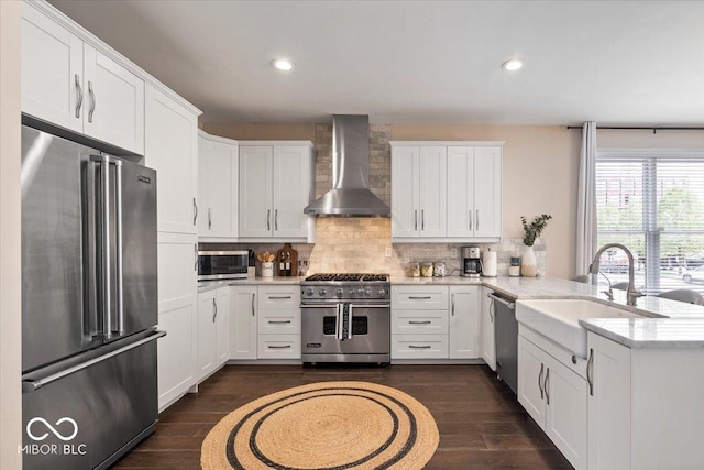 kitchen with a peninsula, premium appliances, dark wood-style flooring, wall chimney exhaust hood, and tasteful backsplash