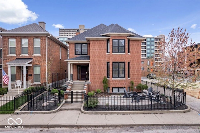 view of front of house with a fenced front yard, brick siding, and a patio area