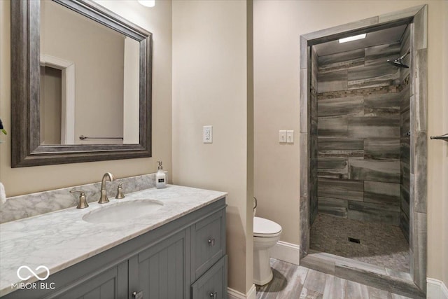 full bath featuring a tile shower, toilet, and vanity