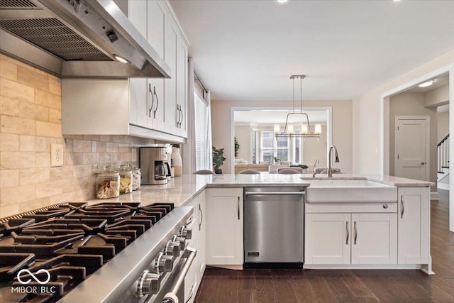 kitchen with light stone counters, dark wood-style floors, custom exhaust hood, a sink, and appliances with stainless steel finishes