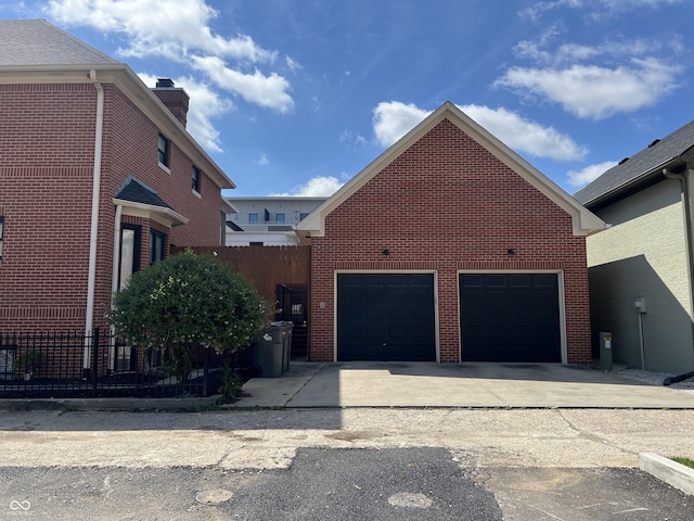 view of property exterior with brick siding, a garage, and fence