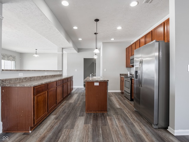 kitchen featuring decorative light fixtures, dark hardwood / wood-style flooring, a center island, stainless steel appliances, and a textured ceiling