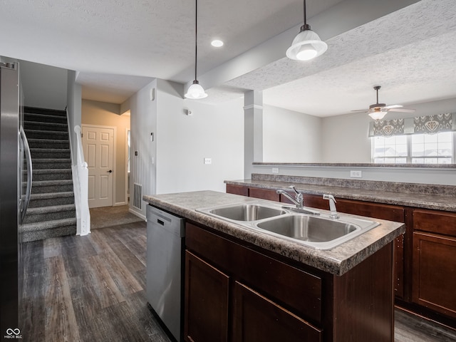 kitchen with stainless steel appliances, hanging light fixtures, a center island with sink, and a textured ceiling