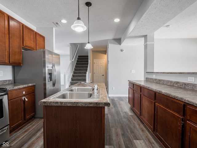 kitchen with sink, a kitchen island with sink, hanging light fixtures, and a textured ceiling