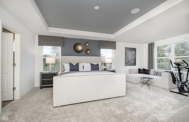 bedroom featuring a tray ceiling, light colored carpet, and baseboards