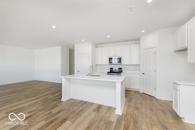 kitchen with a center island with sink, white cabinets, appliances with stainless steel finishes, light countertops, and a sink