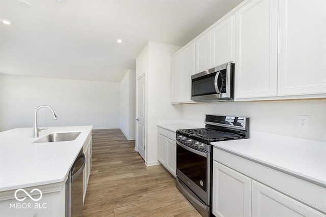 kitchen with a sink, stainless steel appliances, light countertops, and white cabinets