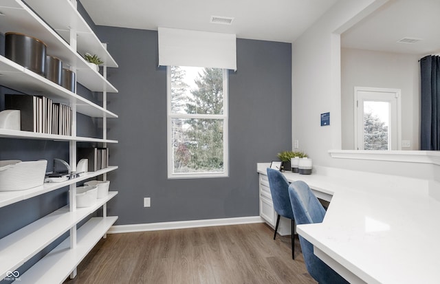 office featuring built in study area, visible vents, baseboards, and wood finished floors