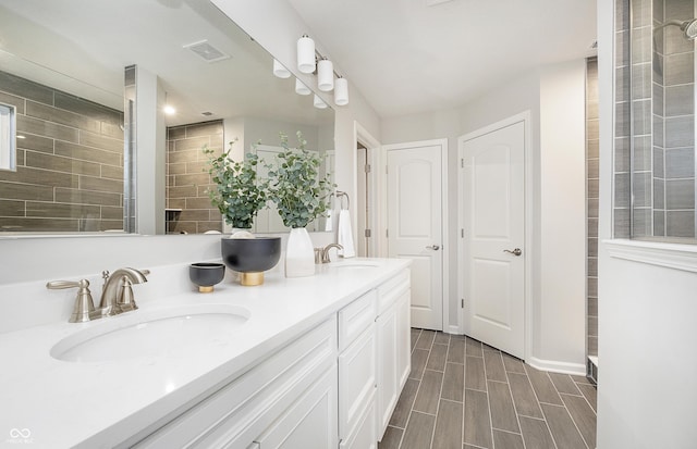 full bath with double vanity, visible vents, a sink, and wood finish floors