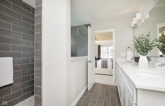 bathroom with ensuite bathroom, a walk in shower, wood finish floors, a sink, and double vanity