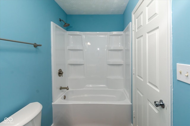 bathroom with a textured ceiling, washtub / shower combination, and toilet