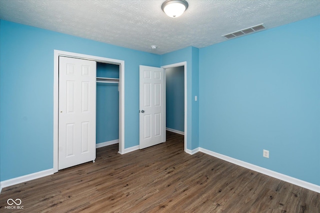 unfurnished bedroom featuring a closet, dark hardwood / wood-style floors, and a textured ceiling