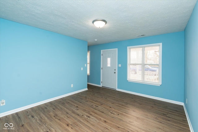 spare room featuring a textured ceiling and dark hardwood / wood-style floors