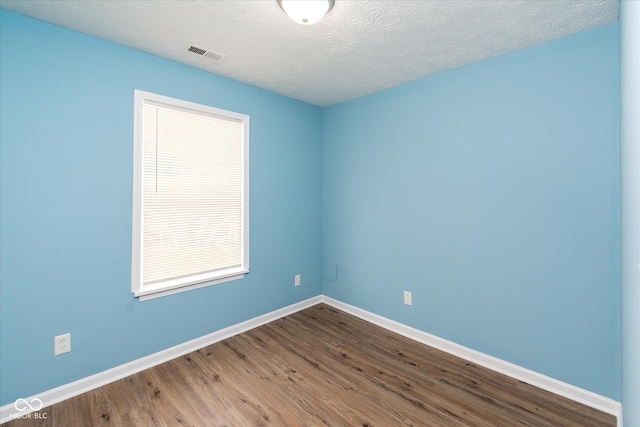 unfurnished room featuring wood-type flooring and a textured ceiling