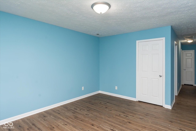 unfurnished room with dark wood-type flooring and a textured ceiling