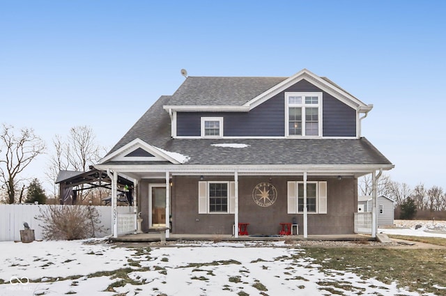 view of front of home with covered porch, a shingled roof, and fence