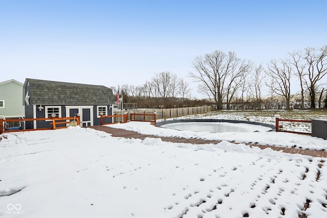 snowy yard with an outdoor structure, a wooden deck, and fence