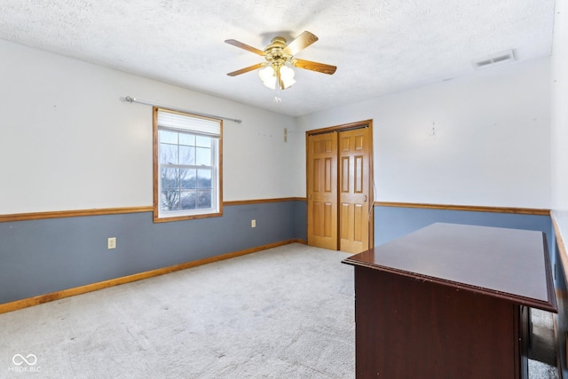 carpeted empty room with visible vents, ceiling fan, a textured ceiling, and baseboards