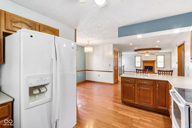 kitchen featuring white appliances, a ceiling fan, light wood-style flooring, light countertops, and a fireplace