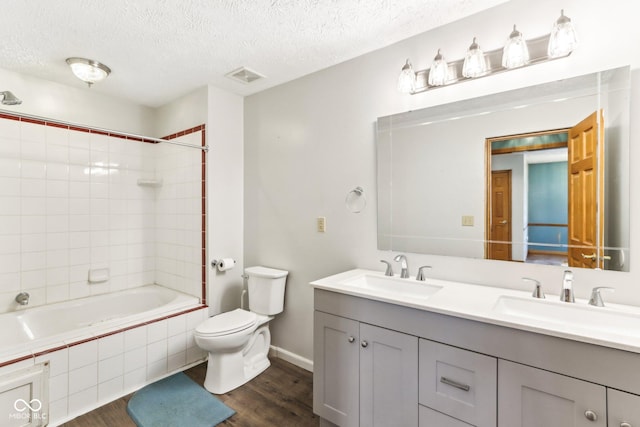 bathroom with toilet, wood finished floors, a sink, and visible vents