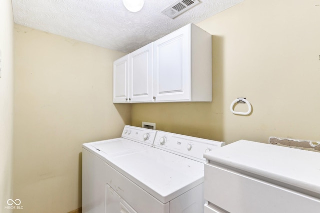 laundry room with visible vents, cabinet space, washer and clothes dryer, and a textured ceiling