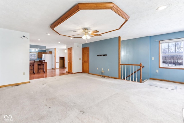 unfurnished living room with carpet floors, a textured ceiling, and baseboards