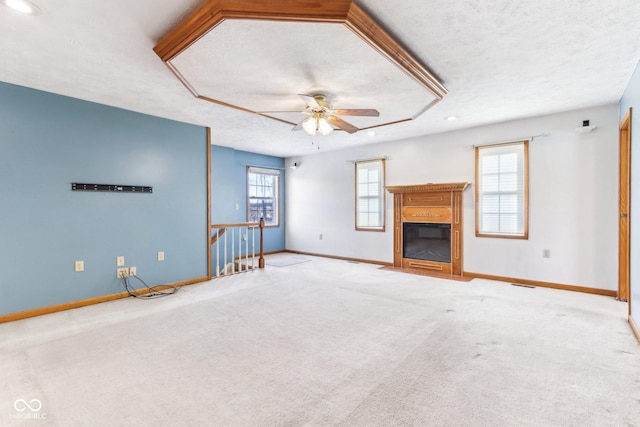 unfurnished living room with baseboards, a ceiling fan, a fireplace with flush hearth, a textured ceiling, and carpet floors