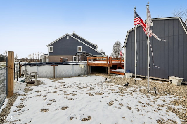 snow covered rear of property featuring a covered pool and a deck