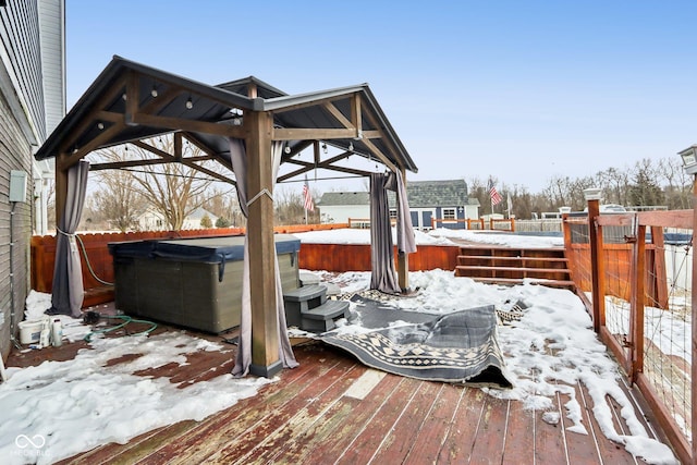 snow covered deck featuring fence and a hot tub