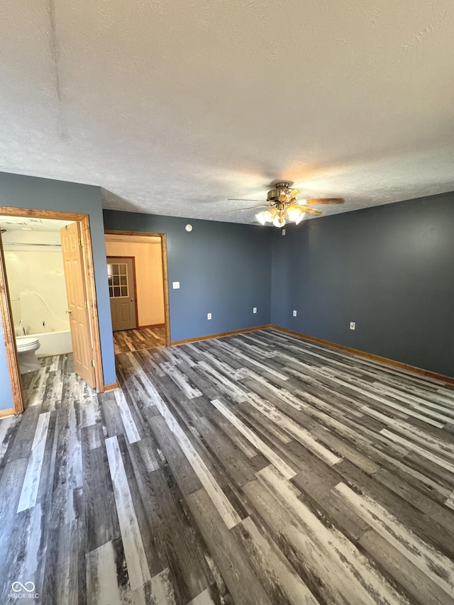 empty room with dark wood-style floors, a textured ceiling, baseboards, and a ceiling fan