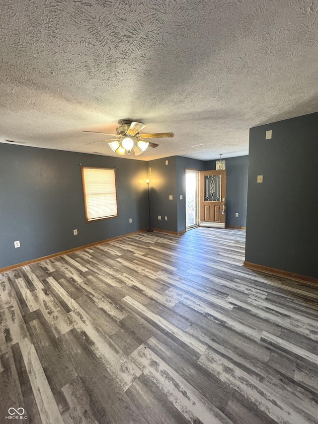 unfurnished living room featuring ceiling fan, a textured ceiling, wood finished floors, and baseboards