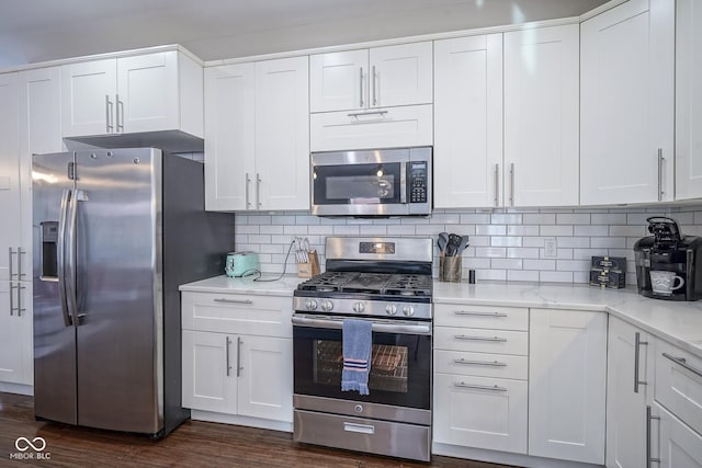 kitchen featuring white cabinetry, dark hardwood / wood-style flooring, stainless steel appliances, light stone countertops, and decorative backsplash