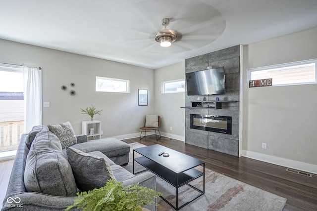 living room featuring a tiled fireplace, hardwood / wood-style flooring, and ceiling fan