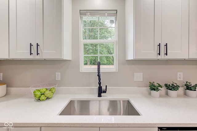 kitchen with light stone countertops, sink, and white cabinetry