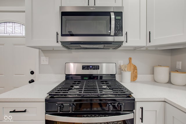 kitchen featuring gas range oven and white cabinets