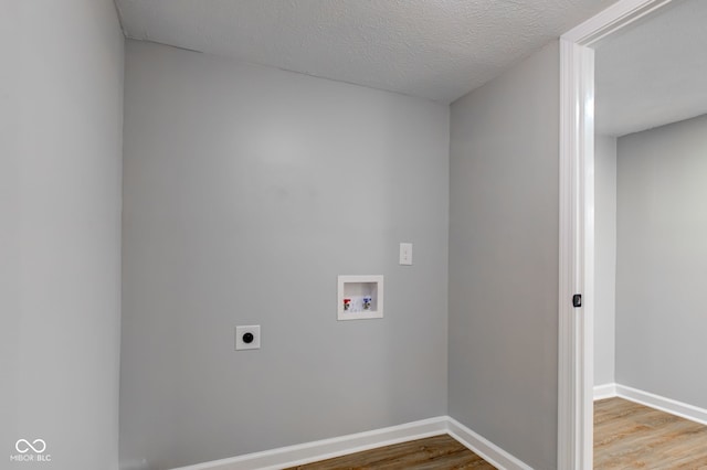 washroom with wood-type flooring, hookup for a washing machine, a textured ceiling, and electric dryer hookup