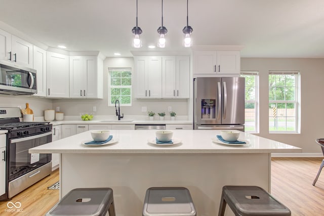 kitchen featuring sink, a kitchen island, hanging light fixtures, and appliances with stainless steel finishes