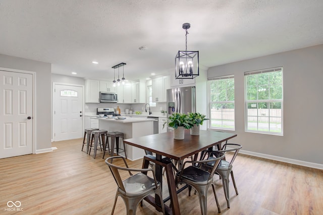 dining space with plenty of natural light, a textured ceiling, sink, and light wood-type flooring