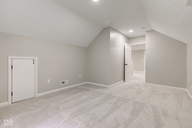 additional living space featuring light colored carpet and lofted ceiling