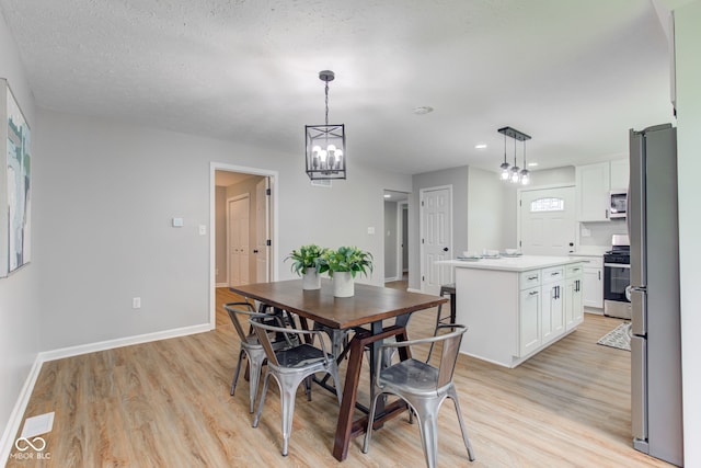 dining space featuring a textured ceiling, an inviting chandelier, and light wood-type flooring