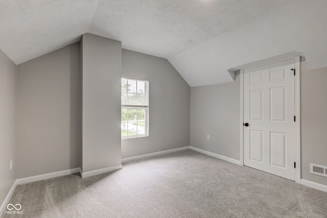 bonus room featuring light colored carpet, a textured ceiling, and lofted ceiling