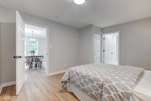 bedroom with a closet, a notable chandelier, and light wood-type flooring