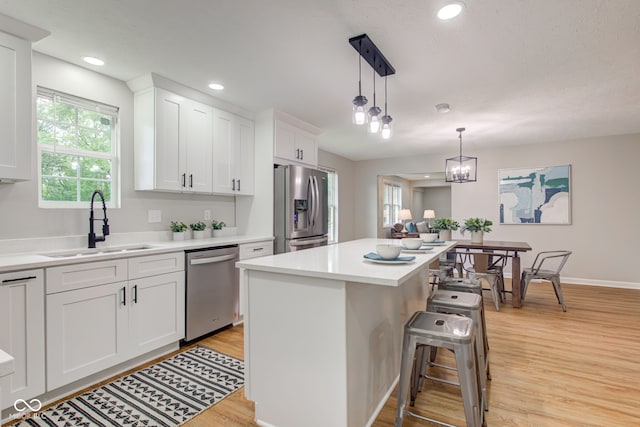 kitchen featuring white cabinets, hanging light fixtures, a kitchen bar, and appliances with stainless steel finishes