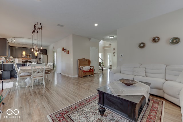 living room with rail lighting and light hardwood / wood-style floors